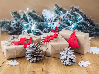 Kraft gift boxes, garland, Christmas decorations, cones on the wooden background. Shallow Selective focus.