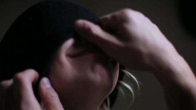 man pulls hat on girl eyes and kisses.