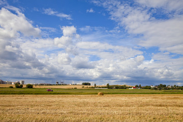 Fototapeta na wymiar Summer sky over farm field with hay bales in Belarus