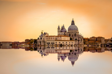 Isolated Basilica di Santa Maria della Salute at orange colors reflected on the water surface, Venice, Italy.
