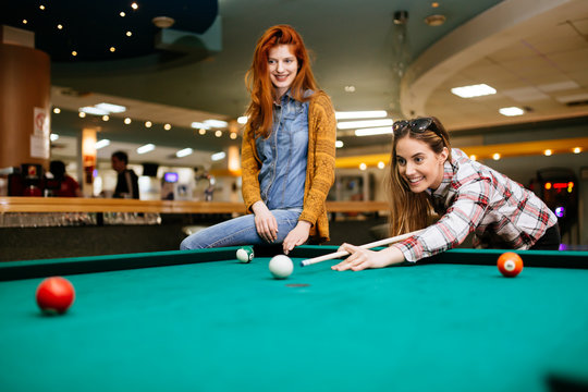 Two female friends playing snooker