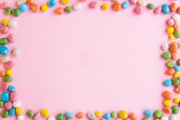 Frame made of sweets scattered on a pink background