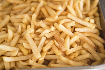 French fries fresh cooked. Restaurant deep fryer, metal container with lots of potatoes fried. Street food, fast food. Potato fries closeup. Roasted tasty potatoes