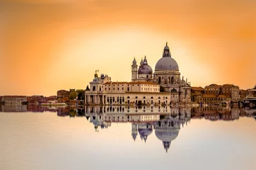 Fototapeten Isolated Basilica di Santa Maria della Salute at orange colors reflected on the water surface, Venice, Italy. © gatsi