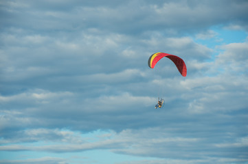 Paramotor flying over the fields in the sky.