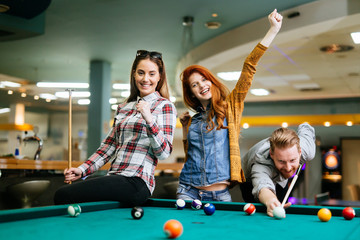 Fototapeta premium Happy friends enjoying playing pool