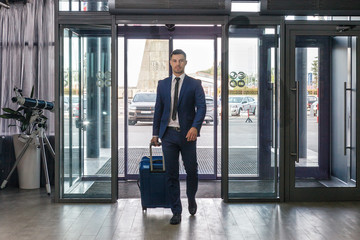 Young businessman with luggage in hotel lobby