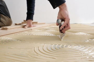 Worker applied adhesive for parquet.Home renovation