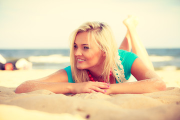 Blonde woman lying on sand.