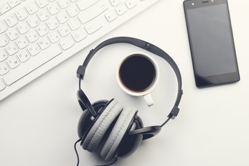 Obraz na płótnie Canvas smartphone, coffee headphones and keyboard on desktop
