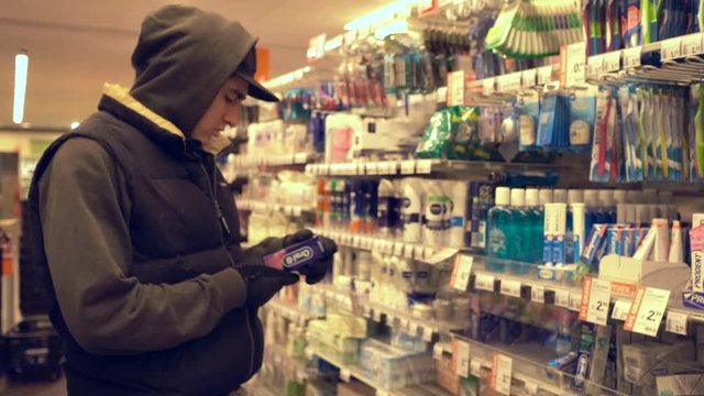 Young caucasian man shopping in a Supermarket and browsing products. Man choosing cosmetics, Toothpaste
