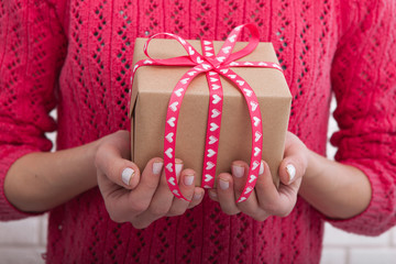 Female hands holding gift box with ribbon.