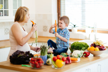 Pregnant woman preparing meal with son