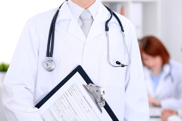 Close-up of a male doctor in a background of doctor and patient