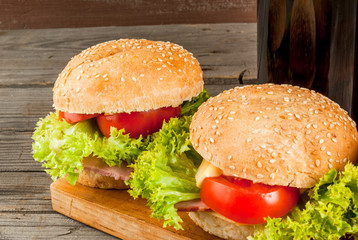 Freshly prepared homemade burger: a bun with sesame seeds, meat, cheese, lettuce, tomato and cheese sauce with beer, copy space
