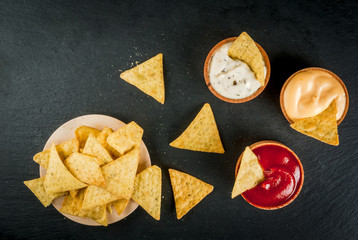 Snack for party, chips, nachos with sauces: tomato (ketchup), cheese and mayonnaise (tartar), top view, copy space