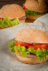 Freshly prepared homemade burgers: a bun with sesame seeds, meat, cheese, lettuce, tomato and cheese sauce, copy space