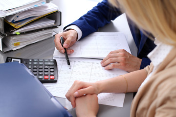 Bookkeeper or financial inspector and secretary making report, calculating or checking balance. Internal Revenue Service inspector checking financial document. Audit concept.