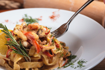 Concept: restaurant menus, healthy eating, homemade, gourmands, gluttony. Pasta with seafood on a fork.