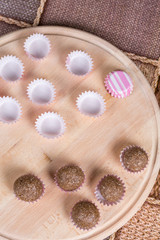 Chocolate balls in paper baskets on the wooden board