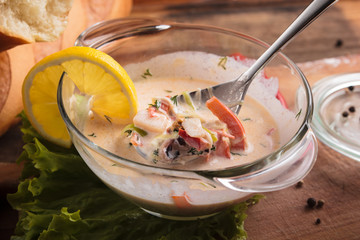 Concept: restaurant menus, healthy eating, homemade, gourmands, gluttony. Creamy soup with seafood on a messy weathered wooden background with ingredients.
