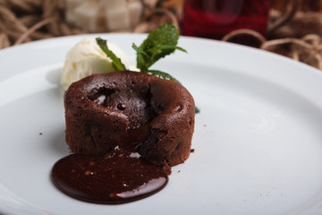 Concept: restaurant menus, healthy eating, homemade, gourmands, gluttony. White plate with chocolate fondant and ice cream on a messy vintage wooden background.