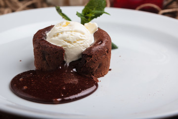 Concept: restaurant menus, healthy eating, homemade, gourmands, gluttony. White plate with chocolate fondant and ice cream on a messy vintage wooden background.