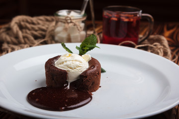 Concept: restaurant menus, healthy eating, homemade, gourmands, gluttony. White plate with chocolate fondant and ice cream on a messy vintage wooden background.