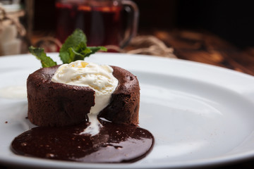 Concept: restaurant menus, healthy eating, homemade, gourmands, gluttony. White plate with chocolate fondant and ice cream on a messy vintage wooden background.