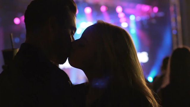 Couple of carefree clubbers kissing and dancing at party, laughing, having fun