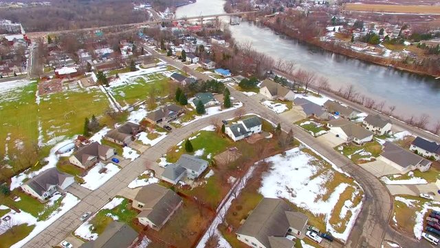 Aerial view of small town USA, neighborhoods, scenic river, springtime. One side of the river is muddy with runoff from a stream just upriver, very interesting to see from above.