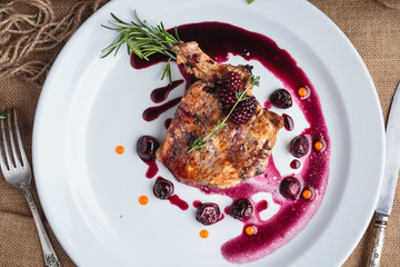 Concept: restaurant menus, healthy eating, homemade, gourmands, gluttony. Pork steak on the bone with cherry-ginger sauce with ingredients on messy sackcloth background. Top-down view.