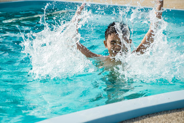 Young asian boy kid child splashing and laughing in swimming pool having fun leisure activity open arms.