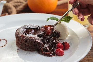 Concept: restaurant menus, healthy eating, homemade, gourmands, gluttony. White plate with chocolate fondant with strawberry and ice cream on a messy vintage wooden background.