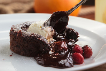 Concept: restaurant menus, healthy eating, homemade, gourmands, gluttony. White plate with chocolate fondant with strawberry and ice cream on a messy vintage wooden background.