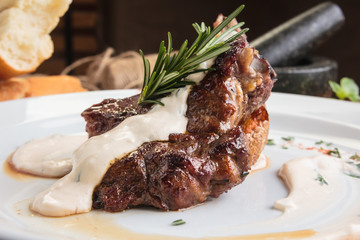 Concept: restaurant menus, healthy eating, homemade, gourmands, gluttony. White plate of lamb rack on wooden table and ingredients on background.