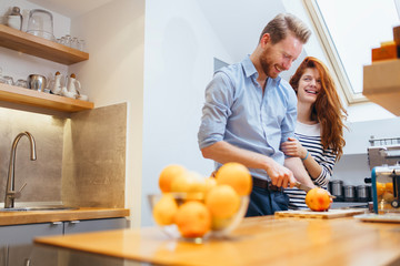 Couple making orange smoothie in kitchen