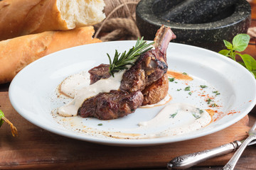 Concept: restaurant menus, healthy eating, homemade, gourmands, gluttony. White plate of lamb rack on wooden table and ingredients on background.