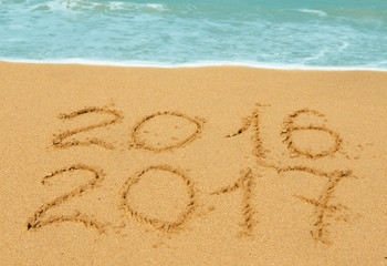 digits  2016 and 2017 on the sand