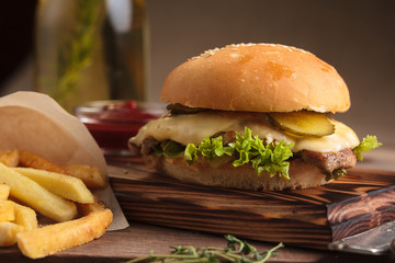 Concept: restaurant menus, healthy eating, homemade, gourmands, gluttony. Classic burger with beef with ingredients and french fries on messy vintage wooden background.