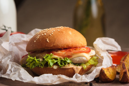 Concept: Restaurant Menus, Healthy Eating, Homemade, Gourmands, Gluttony. Classic Burger With Chicken With Ingredients And Potato Wedges On Messy Vintage Wooden Background.