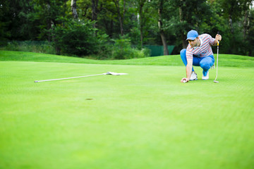 Obraz premium Golf player marking ball on the putting green