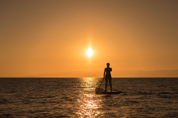 woman silhouette at paddle board in sunset