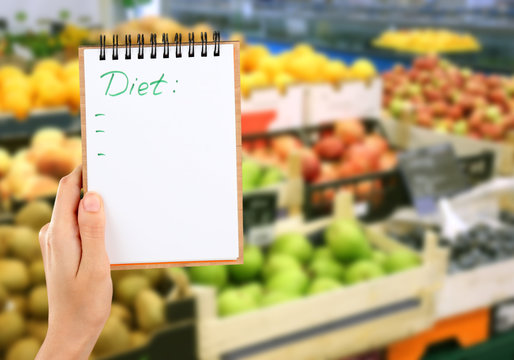 Woman with notebook in store, closeup. Text DIET on paper.