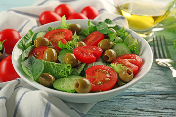 Tasty vegetable salad with fork on kitchen table
