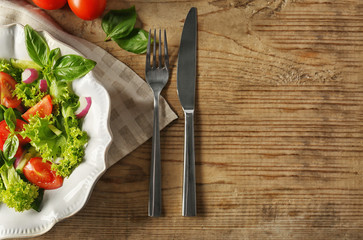 Tasty vegetable salad with cutlery on kitchen table