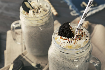 Delicious milk dessert with sweets in glass jugs on table, closeup