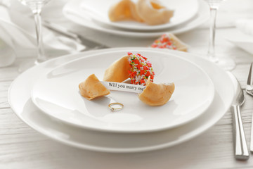 Offer of marriage with fortune cookies and ring on white plate closeup