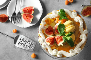 Delicious creamy cake with figs and berries on light grey background