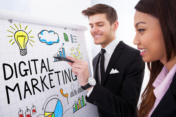 Two Businesspeople Discussing Digital Marketing On Flipchart